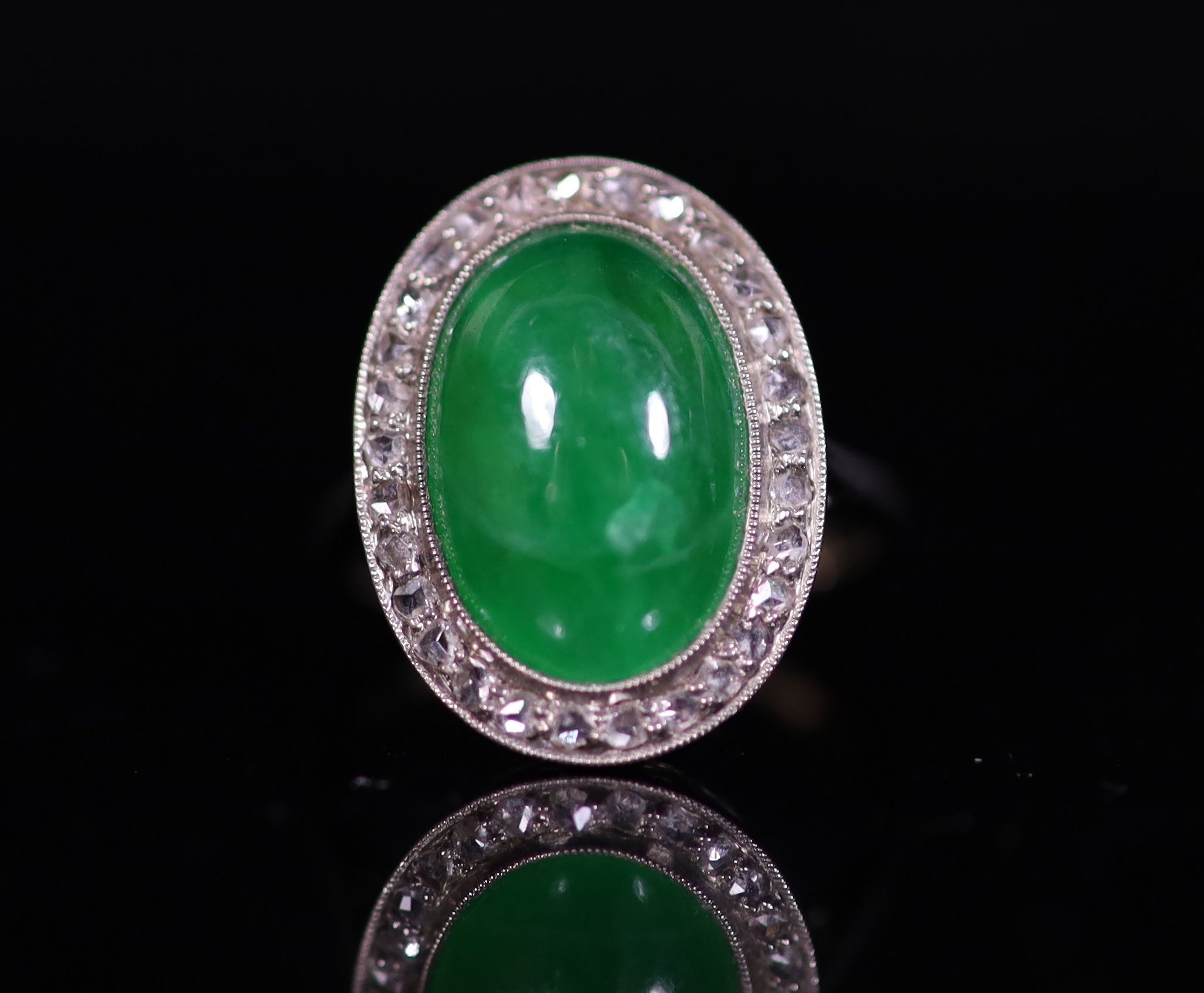 A 1920's 18ct white gold, oval cabochon jadeite and rose cut diamond millegrain set dress ring